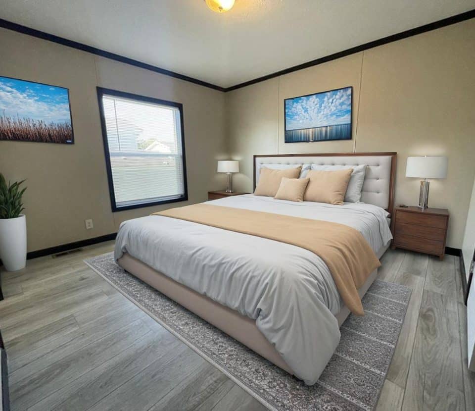 A modern bedroom with a large bed, beige and white bedding, two wooden nightstands with lamps, a potted plant, two landscape photos on the walls, and a window letting in natural light.