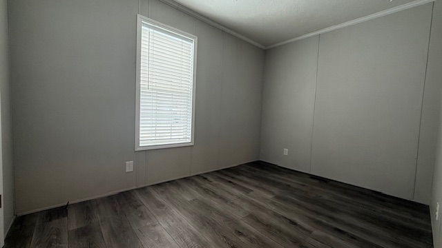 An empty room with gray walls, a single window with white blinds, dark wood flooring, and white ceiling trim. There are no furnishings or decorations visible.