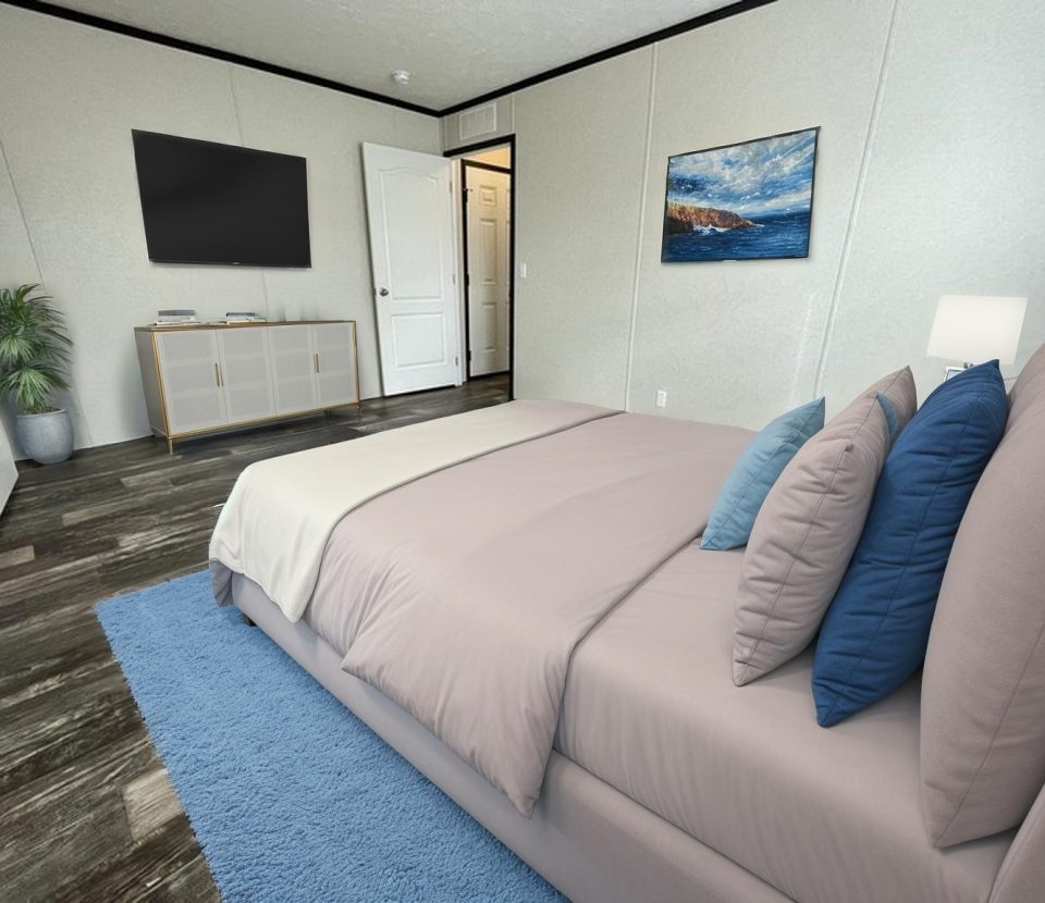 A modern bedroom with a neatly made bed, blue and gray bedding, a blue rug, a wall-mounted TV, a sideboard, a plant, a closed door, and a painting on a white wall.