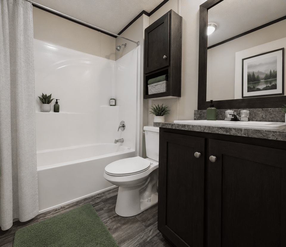 Modern bathroom with a white bathtub and shower, dark wood cabinets, gray countertop, white toilet, green towels and bath mat, potted plants, and framed landscape art on the wall.